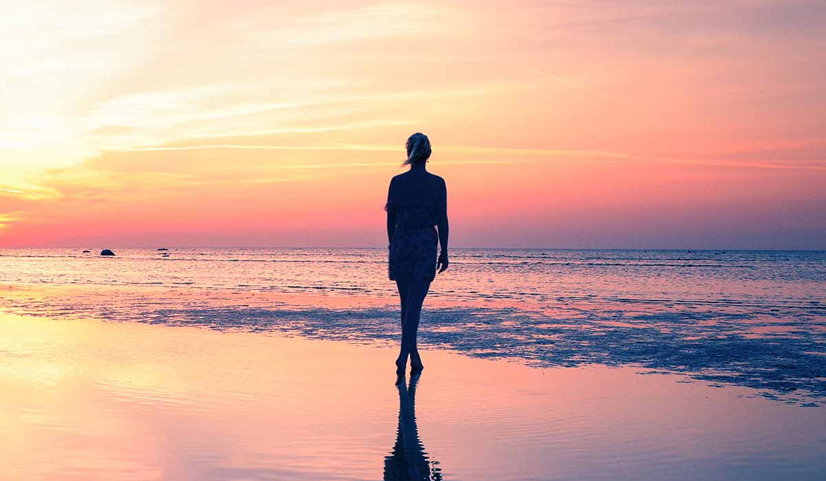 Frau spaziert im seichten Teil des Meeres am Strand entlang